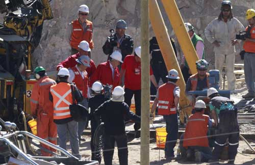 Chilean President Sebastian Pinera (C, looking down) walks with workers to visit the area where the operation to rescue the 33 trapped miners is being prepared, at the San Jose mine in Copiapo Oct 12, 2010. [China Daily/Agencies]