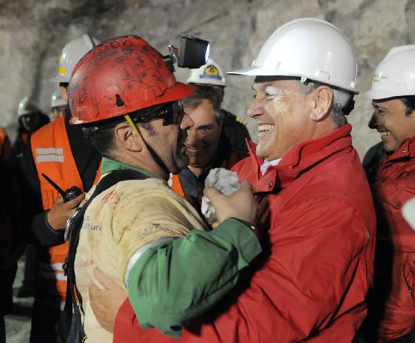 In this image released by the government of Chile, the second miner Mario Sepulveda (L), one of the 33 trapped miners, hugs Chilean President Sebastian Pinera at the San Jose mine in Copiapo, Chile, Oct. 12, 2010. The operation to lift out the 33 miners trapped for over two months in northern Chile is under way right now.[Jose Manuel de la Maza/Xinhua/Government of Chile]