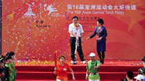 The first torchbearer Yang Wei(Center L) runs with the torch during the torch relay for the 16th Asian Games in Zhongshan.