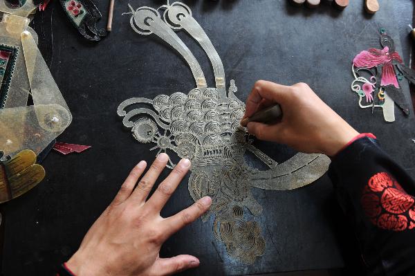 He Zehua carves a piece of leather to make a shadow play puppet in his museum in Shuidong Town, Xuancheng City of east China's Anhui Province, Oct. 12, 2010.