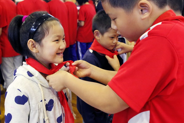 Sixteen children with overseas citizenship put on red scarves and become members of the Young Pioneer League of China to celebrate the 61st anniversary of its founding in Zhuji, Zhejiang province, Oct 12, 2010. [Xinhua] 