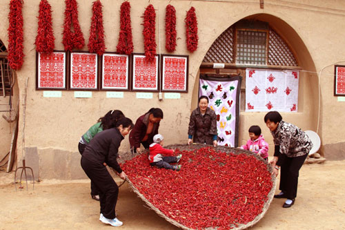 Villagers work on drying red chili peppers in a yard in Huoyanshan village of Yan&apos;an, Shaanxi province, Oct 13, 2010. [Xinhua] 