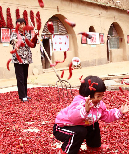 A child plays with red chili peppers in Huoyanshan village of Yan&apos;an, Shaanxi province, Oct 13, 2010. [Xinhua] 