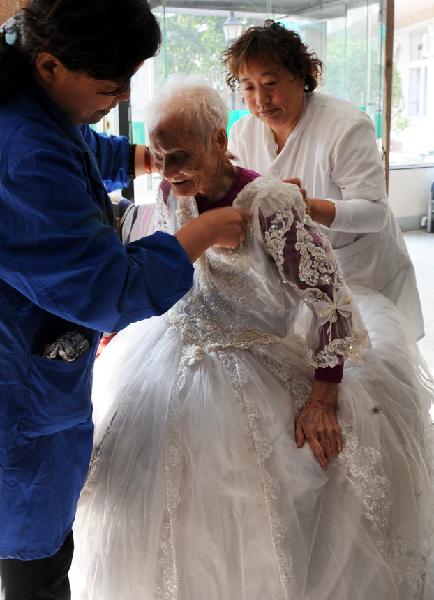Chen Laikang (C), who is 101 years old, is dressed up for photos in a suit of wedding dress in Tianjin, north China, Oct. 13, 2010. Chen realized her dream of taking pictures in wedding dress as the Double Ninth Festival draws on. The festival is also known as &apos;Chongyang Festival&apos; or &apos;Old Veneration Festival&apos;, a Chinese traditional occasion to pay respect to the aged. [Xinhua] 