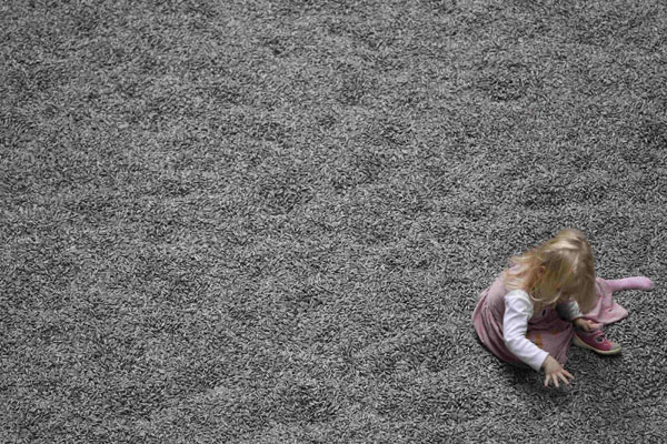 A girl plays on the new installation by Ai Weiwei entitled &apos;Sunflower Seeds&apos;, at its unveiling in the Turbine Hall at the Tate Modern gallery, in London on Oct 11, 2010. Chinese conceptual artist Ai Weiwei has filled the hall with more than 100 million life-sized sunflower seed husks made out of porcelain. The hand-crafted seeds were individually formed and painted by a number of specialists from Jingdezhen, East China&apos;s Jiangxi province. [China Daily/Agencies] 