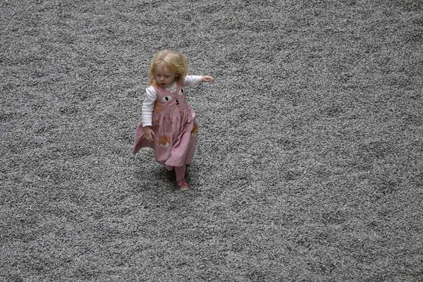 A girl runs on the new installation by Ai Weiwei entitled &apos;Sunflower Seeds&apos;, at its unveiling in the Turbine Hall at the Tate Modern gallery, in London on Oct 11, 2010. [China Daily/Agencies]