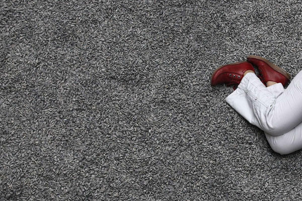 A woman lays on the new installation by Ai Weiwei entitled &apos;Sunflower Seeds&apos;, at its unveiling in the Turbine Hall at the Tate Modern gallery, in London on Oct 11, 2010. [China Daily/Agencies] 