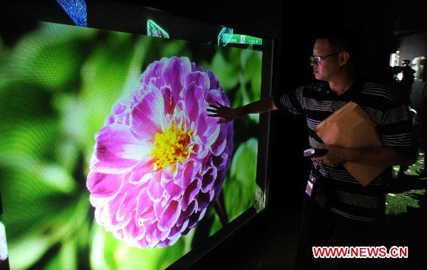 A visitor touches a big touch screen at the Pavilion of Future at 2010 Taipei International Flora Expo in Taipei, south China's Taiwan, Oct. 13, 2010. The 15 theme zones at the Pavilion of Future opened to visitors for the first time on Wednesday. With the use of advanced technologies, the pavilion showcased the future environment where human and plants coexist harmoniously. [Xinhua/Wu Ching-teng]