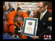 Khagendra Thapa waves after receiving the certificate from Marco Frigatti (R), Vice-President of   Guinness Book of World Records, at a function in Pokhara, west of Kathmandu October 14, 2010. [Xinhua]