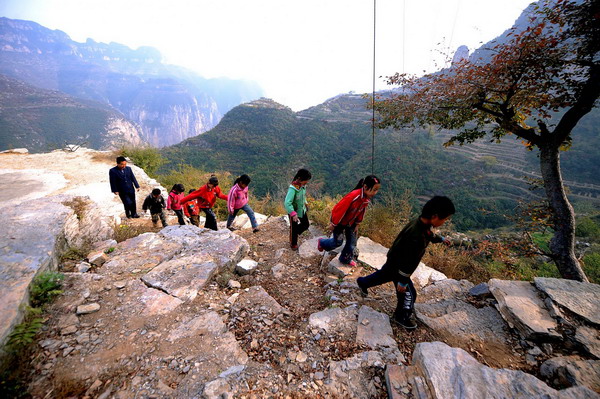 Yuan Zichao and his students return to the classroom from the playground at Xichan School, Changzhi, Shanxi province, Oct 14, 2010.Xichan Primary School, which is located on a cliff in a village isolated by Taihang Mountains, is a more than two-hour drive on the bumpy mountain road from town. The school in Changzhi has eight students in three grades. Its only teacher, Yuan Zichao, has been teaching there alone for 14 years. [Xinhua]