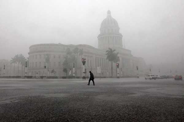 A man crosses the street near the Capitol building during thunderstorms in Havana October 14, 2010. The rains of tropical storm Paula began affecting Cuba since early Thursday morning, mainly in Pinar del Rio province in the west of the island state, according to the National Institute Meteorology (INSMET). [Xinhua/Reuters]