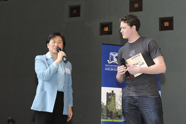 Guo Xiaojuan (L), an official at the Consulate General of China to Melbourne, gives away souvenirs to a student who played cross-talk during the Chinese Culture Festival at the University of Melbourne, Oct 14, 2010. [Xinhua] 