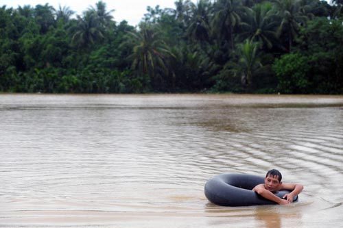 A man swims in flood water where a field is submerged in Qionghai, South China's Hainan province, Oct 16, 2010. [Xinhua]