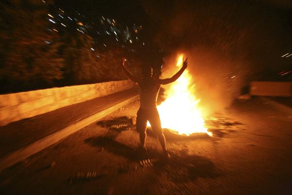 A Palestinian youth stands by a fire during the clash with Israeli border police in the East Jerusalem neighbourhood of Silwan Oct. 17, 2010. [Muammar Awad/Xinhua]