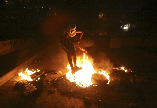 A Palestinian youth jumps over a fire during the clash with Israeli border police in the East Jerusalem neighbourhood of Silwan Oct. 17, 2010. [Muammar Awad/Xinhua] 