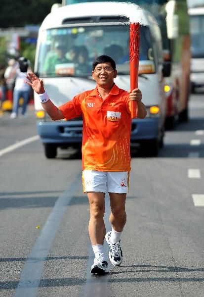 Torchbearer Mo Buxing runs with the torch during the Torch Relay for the 16th Asian Games in Dongguan, South China's Guangdong Province, Oct. 17, 2010. (Xinhua/Liu Dawei) 