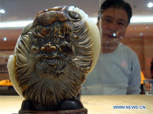 A visitor looks at a jade sculpture on an exhibition in Suzhou, east China's Jiangsu Province, Oct. 17, 2010. More than 300 jade sculpture works made by Su Ran, an artist of jade sculptures, were seen on a 10-day jade sculpture exhibition kicked off on Saturday. 