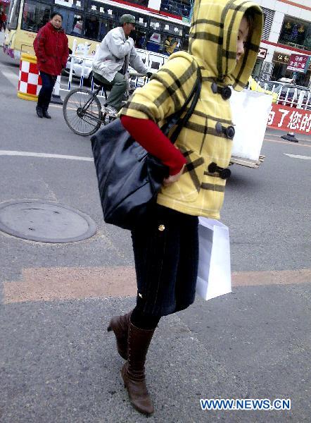 A woman in winter clothes walks on the street in Qiqihar, northeast China&apos;s Heilongjiang Province, Oct. 16, 2010. Northeast China witnessed a significant temperature drop on Saturday. 