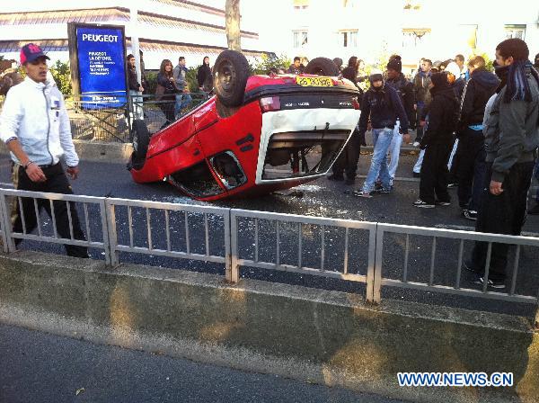 Students overturn a car during a demonstration in the northern suburbs of Nanterre in Paris, France, Oct. 18, 2010. Several cars were torched and hundreds of young people were arrested in the French capital Paris and Lyon in the south, after chaos emerged during demonstrations of secondary school students, who joined the unions' strike against pension reforms. [Gao Zixuan/Xinhua]