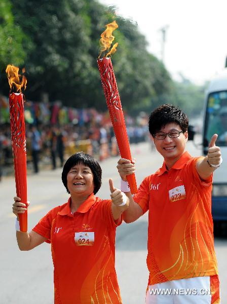 The torchbearer Ren Yongquan(R) poses with Huang Suning during the torch relay for the 16th Asian Games in Shenzhen, south China's Guangdong Province, Oct. 18, 2010. (Xinhua/Liu Dawei) 