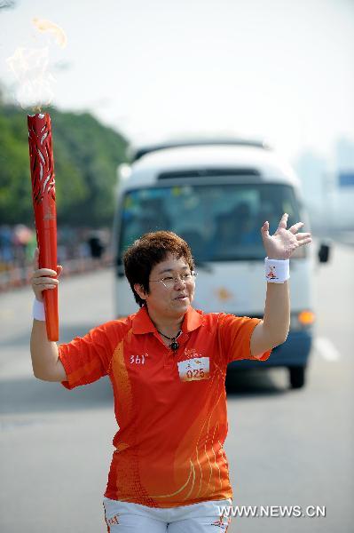 The torchbearer Zhong Shidan runs with the torch during the torch relay for the 16th Asian Games in Shenzhen, south China's Guangdong Province, Oct. 18, 2010. (Xinhua/Liu Dawei)