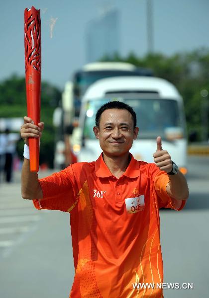 The torchbearer Hang Guoqiang runs with the torch during the torch relay for the 16th Asian Games in Shenzhen, south China's Guangdong Province, Oct. 18, 2010. (Xinhua/Liu Dawei)