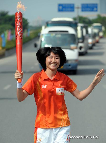 The torchbearer Huang Qiaoyan runs with the torch during the torch relay for the 16th Asian Games in Shenzhen, south China's Guangdong Province, Oct. 18, 2010. (Xinhua/Liu Dawei)