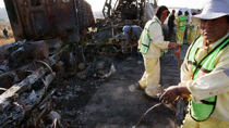 Workers clean the area near the remains of a bus and another vehicle in San Luis Potosi, outside Queretaro, Mexico, on Oct. 18, 2010.