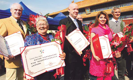 Bruce Buntain, Lorene Mary Habib and Ernst Hurne (left to right), hold their honorable volunteer certificates on Saturday which were awarded for helping Beijingers learn foreign languages. [Zou Hong/China Daily]