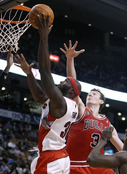 Chicago Bulls center Omer Asik, rear, tries to defend as Toronto Raptors forward Reggie Evans drives to the basket during the first half of an NBA preseason basketball game in Toronto, Oct. 20, 2010. Bulls beat Raptors 110-103.(Xinhua/Reuters Photo)