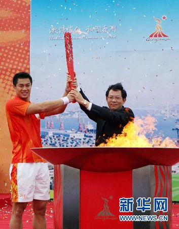 The 80th and last torchbearer Huang Liangcai (left), a men's foil Asian champion, and Zheng Renhao, Executive Vice Mayor of Shantou, present the torch after lighting the cauldron.