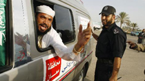 An international peace activist (L) gestures from inside a vehicle next to a Hamas policeman upon his arrival at the Rafah border crossing in the southern Gaza Strip October 21, 2010.