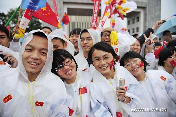 People cheer in the rain during the torch relay for the 16th Asian Games in Jieyang City, south China&apos;s Guangdong Province, Oct. 23, 2010. A total of 80 torchbearers on Saturday took part in the torch relay of the 2010 Asian Games in Jieyang. 