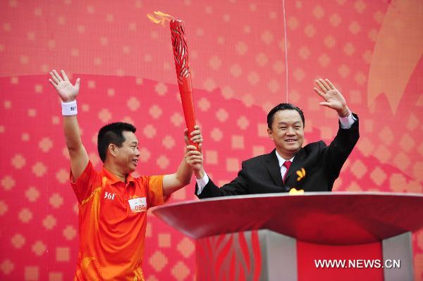 The last torchbearer Chen Zhiqiang (L) holds the torch with Chen Yiwei, mayer of the Jieyang City, after lighting the cauldron during the torch relay for the 16th Asian Games in Jieyang City, south China&apos;s Guangdong Province, Oct. 23, 2010. 