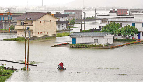 A motorcyclist walks through floodwater after Typhoon Megi hit Ilan county in northern Taiwan on Friday, Oct 22, 2010. [China Daily] 