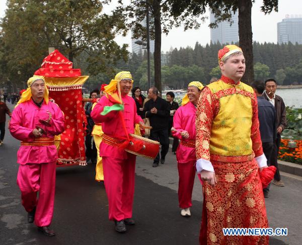 A bridegroom from Germany(Front) walks in a traditional Chinese wedding parade in Nanjing, capital of east China's Jiangsu Province, Oct. 23, 2010. 