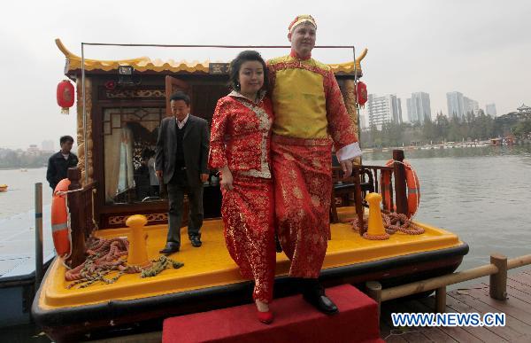 A bridegroom from Germany together with his Chinese bride goes ashore from a pleasure-boat during a traditional Chinese wedding parade in Nanjing, capital of east China's Jiangsu Province, Oct. 23, 2010. 