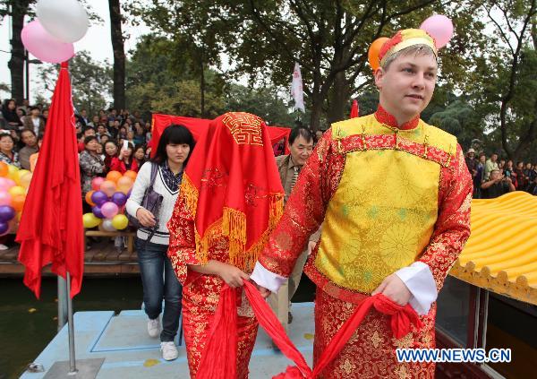 A bridegroom from Germany together with his Chinese bride boards onto a pleasure-boat during a traditional Chinese wedding parade in Nanjing, capital of east China's Jiangsu Province, Oct. 23, 2010. 