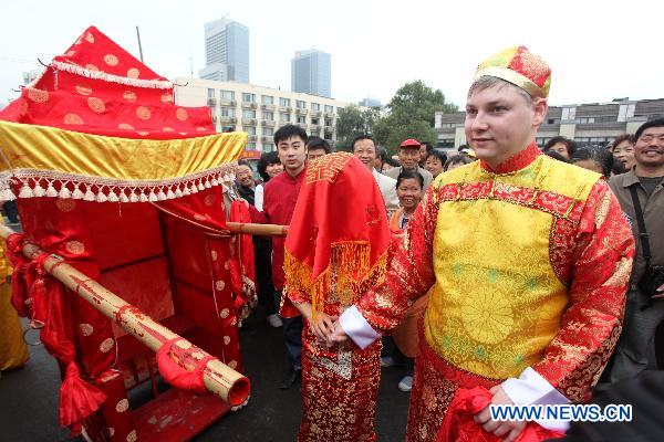 A bridegroom from Germany(R) together with his Chinese bride stands in front of a bridal sedan chair during a traditional Chinese wedding parade in Nanjing, capital of east China's Jiangsu Province, Oct. 23, 2010. 