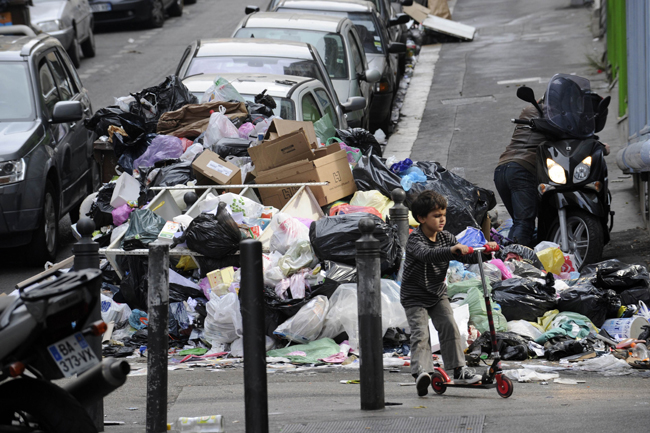 A child rides his scooter in front garbage piled on October 24, 2010 in a street of Marseille, as a result of a strike by rubish collectors since October 12 to protest against French President&apos;s bid to raise the retirement age. The pensions reform bill was approved by the Senate on October 22, and the text will be reconciled October 25 with the draft passed earlier by the lower house. However, strikes have continued across the industry. [Xinhua] 