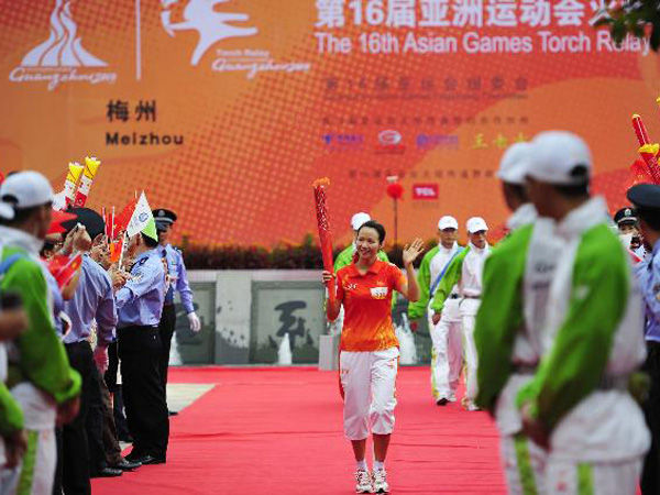 The first torchbearer Chen Qiuqi (C) holds the torch during the Torch Relay for the 16th Asian Games in Meizhou City, South China's Guangdong Province, Oct. 24, 2010. (Xinhua/Liang Xu) 