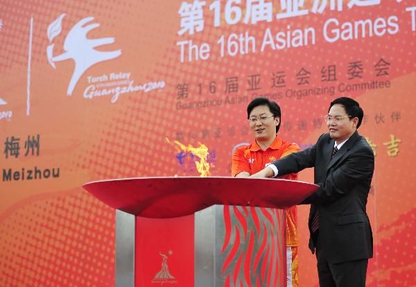 The last torchbearer Ning Yuanxi (L) and Zhu Zejun, the acting mayor of Meizhou City, light the cauldron at the end of the Torch Relay for the 16th Asian Games in Meizhou City, South China's Guangdong Province, Oct. 24, 2010. (Xinhua/Liang Xu) 