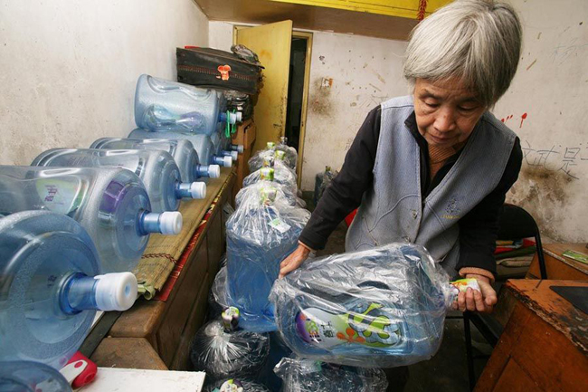 Gao Meiyun, 70, carries water at Yang village of Shijingshan district on Ocotber 19, 2010 in Beijing, China. Gao, weight 37.5kg, for supporting her disabled son and retarded grandson has to deliver 40 - 60 containers water which per one weight 20kg every day. [sohu.com]