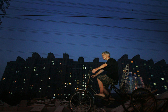 Gao Meiyun, 70, rides to deliver water at Yang village of Shijingshan district on July 29, 2010 in Beijing, China. Gao, weight 37.5kg, for supporting her disabled son and retarded grandson has to deliver 40 - 60 containers water which per one weight 20kg every day. [sohu.com]