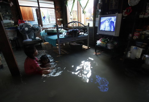 Residents watch television at their flooded house in Bangkok October 25, 2010. Floodwaters from northeast provinces, which have swamped thousands of acres of farmland, have spread to the Thai capital. At least 38 people have been reported dead in 13 provinces that were hardest hit by flood during October 10-24, according to Medical Emergency Institute of Thailand (NIEM) Sunday.[China Daily/Agencies] 