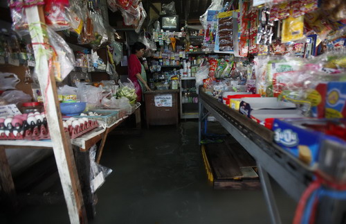 A shopkeeper stands in her flooded store in Bangkok October 25, 2010. Floodwaters from northeast provinces, which have swamped thousands of acres of farmland, have spread to the Thai capital.[China Daily/Agencies] 