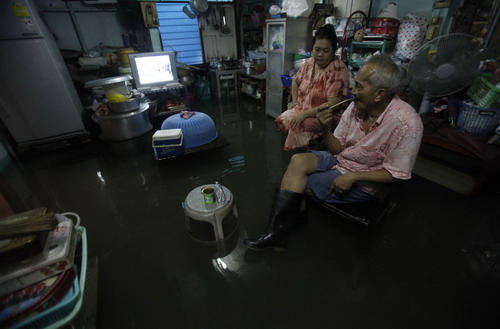 Residents watch television at their flooded house in Bangkok October 25, 2010. Floodwaters from northeast provinces, which have swamped thousands of acres of farmland, have spread to the Thai capital.[China Daily/Agencies] 