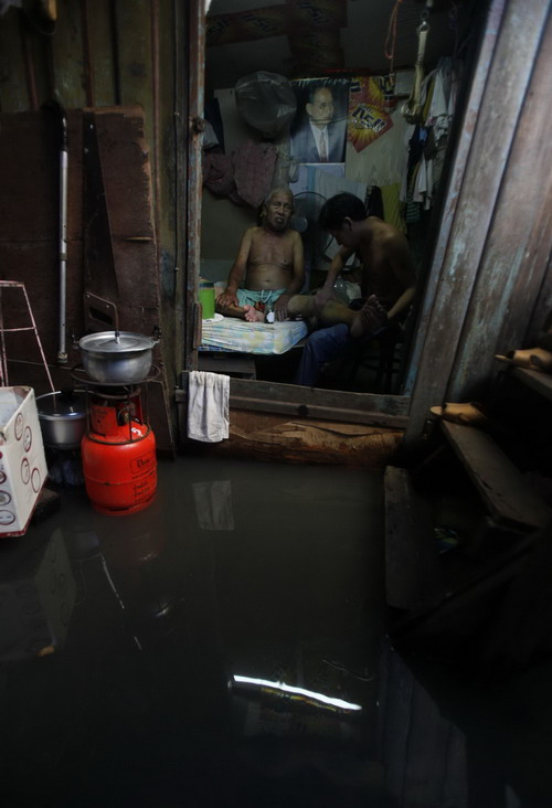 A resident attends to his father in their flooded house in Bangkok October 25, 2010. Floodwaters from northeast provinces, which have swamped thousands of acres of farmland, have spread to the Thai capital.[China Daily/Agencies] 