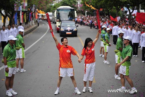 Torchbearer, China's famous speed skater Ye Qiaobo (R) poses with another torchbearer Teng Wenpeng during the torch relay for the 16th Asian Games in Heyuan City, south China's Guangdong Province, Oct. 25, 2010. (Xinhua/Liang Xu)