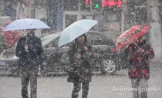 People walk through snow and try to protect themselves with umbrellas in Harbin, Northeast China&apos;s Heilongjiang province, Oct 25, 2010. [Asianewsphoto] 